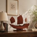 Chinese Fu Chuan warship model displayed on a dark walnut sideboard with ceramic lamp, Chinese books, and green plant in warm afternoon light