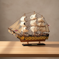 HMS Victory wooden ship model on wooden desk – handcrafted British warship collectible with white sails and yellow-black hull