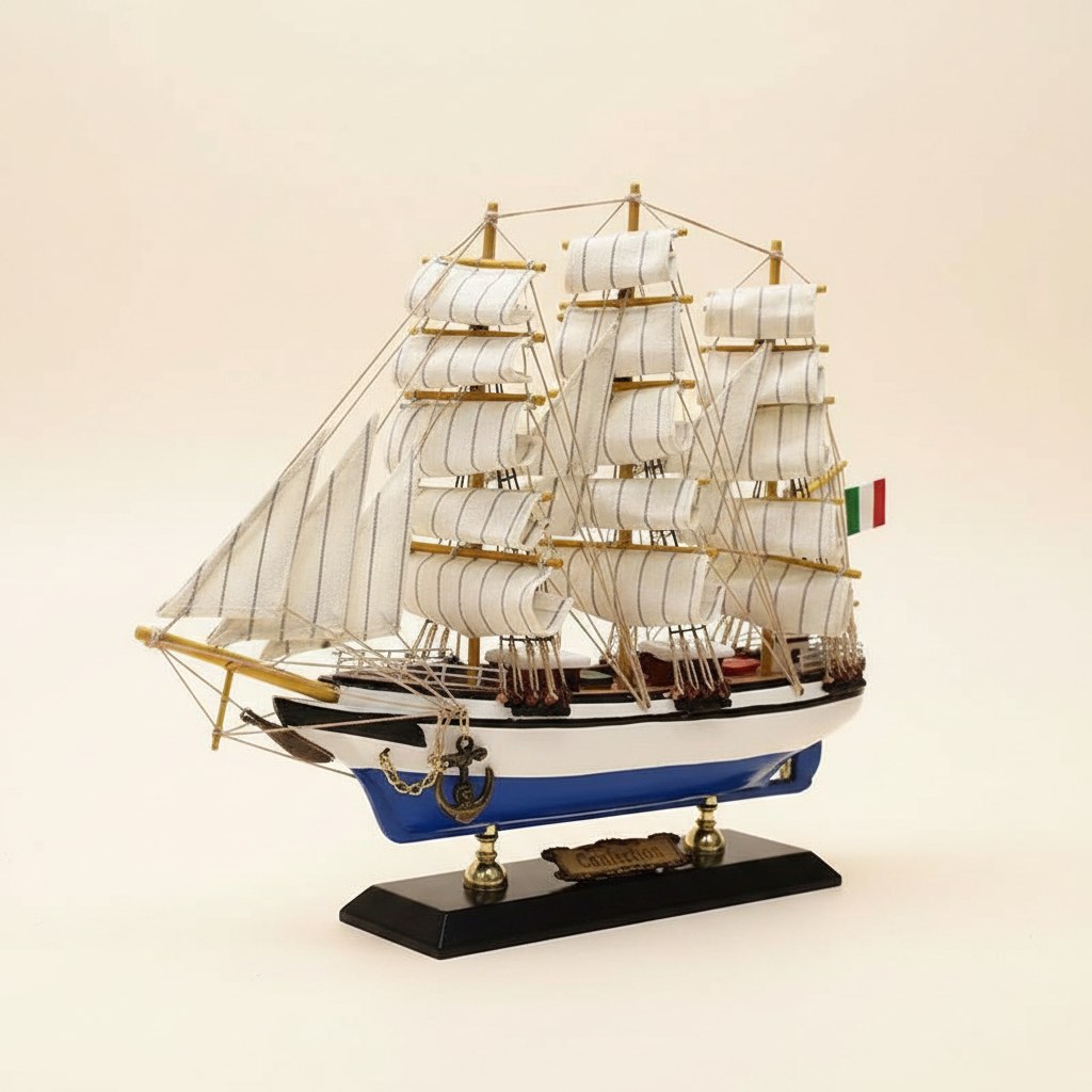  Rear 3/4 angle of Italian Confection tall ship wooden model on cream background, showing three-mast rigging structure, white square-rigged sails, Italian flag, blue-and-white hull stern section, and black display base with brass nameplate