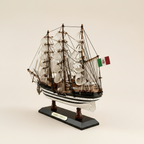 Rear 3/4 angle of Amerigo Vespucci Italian Navy tall ship wooden model on cream background, showing three-mast rigging structure, white square-rigged sails, Italian Navy flag at stern, black-and-white striped hull, and black display base with gold AMERIGO VESPUCCI nameplate

