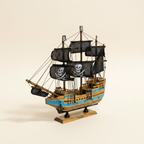 Modello in legno di nave pirata, vista frontale a 3/4, con tre alberi, vele nere con teschio, scafo a righe blu e base nera