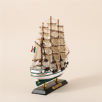 Front bow-on view of Cuauhtémoc Mexican Navy tall ship wooden model on cream background, showing three-mast full sail configuration, rope rigging, white hull with teal-green waterline, Mexican flag, gold decorative hull trim, and black display base with gold Cuauhtemoc nameplate