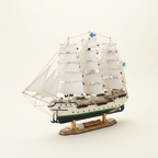 Suomen Joutsen wooden ship model front 3/4 view – three-masted barque with full white sails, green-black hull, rope rigging and Finnish flag