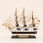 Side view of the A.R.C. Gloria ship model featuring a white hull, green stripe, cream fabric sails, wooden masts, detailed pulleys and rope rigging.