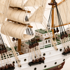 Close-up of the A.R.C. Gloria model ship deck, showing fabric sail stitching, wooden masts, rope rigging, pulleys, railings and handcrafted cabin details.