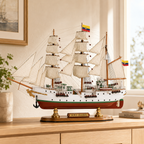 A.R.C. Gloria wooden tall ship model displayed on a light wood cabinet in a bright modern interior, featuring cream fabric sails, detailed rigging, Colombian flags, white hull, green stripe, red lower hull and polished wooden display base.