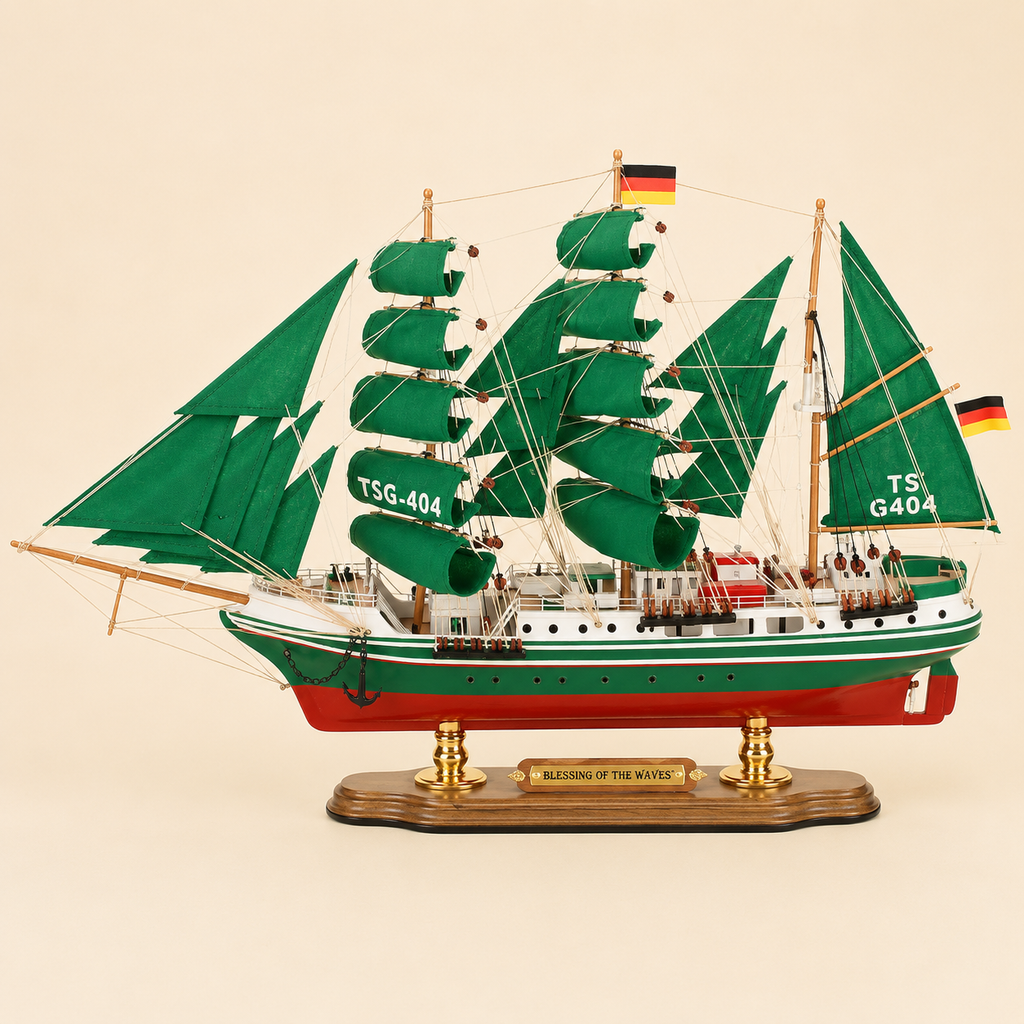 Side view of the Alexander von Humboldt three-masted tall ship model featuring emerald green sails, fine rope rigging, white and green hull, red lower hull, deck cabins and gold-supported wooden stand.