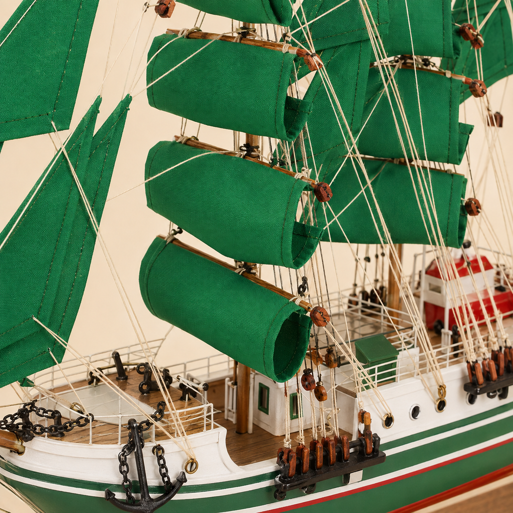 Close-up of the Alexander von Humboldt model ship showing textured green sails, wooden spars, rope rigging, pulleys, deck railings, cabins, anchor chains, portholes and handcrafted nautical details.