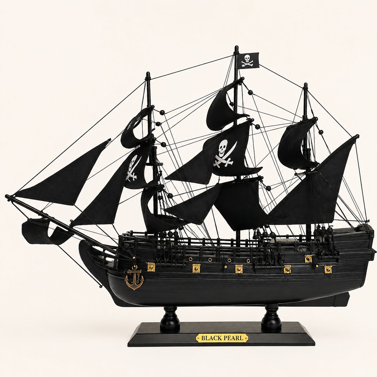 Side view of the Black Pearl three-masted pirate ship model featuring black fabric sails, skull-and-crossbones designs, intricate rigging, black wooden hull, gold decorative fittings and black display stand.