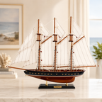 Atlantic three-mast wooden ship model displayed on white marble surface in a bright coastal home setting, handcrafted sailboat with three wooden masts, white canvas sails, black lacquered hull, and brass porthole details on black display stand