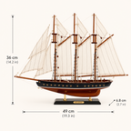 Atlantic wooden ship model size chart showing dimensions 49 cm length by 6.8 cm width by 36 cm height (19.3 x 2.7 x 14.2 inches), handcrafted three-mast sailboat on black display stand