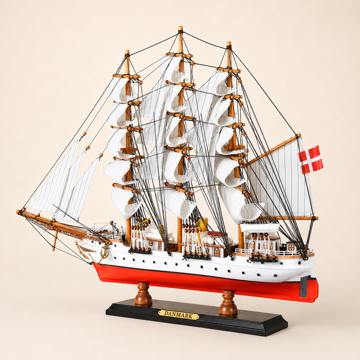 Rear 45-degree view of the Danmark model ship showing the stern, rear deck structures, Danish flag, layered sails, detailed rigging and black wooden display base.