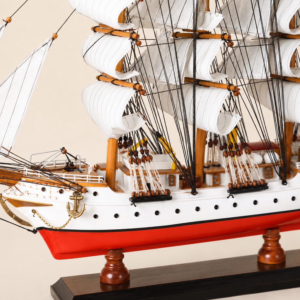 Close-up of the Danmark ship model showing textured white sails, black rope rigging, wooden pulleys, deck cabins, railings, portholes, anchor and handcrafted details.