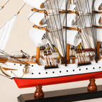 Close-up of the Danmark ship model showing textured white sails, black rope rigging, wooden pulleys, deck cabins, railings, portholes, anchor and handcrafted details.