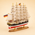 Rear 45-degree view of the Preussen wooden ship model showing the stern, rear deck, German flag, five masts, layered sails, detailed rigging, propeller and polished wooden display base.