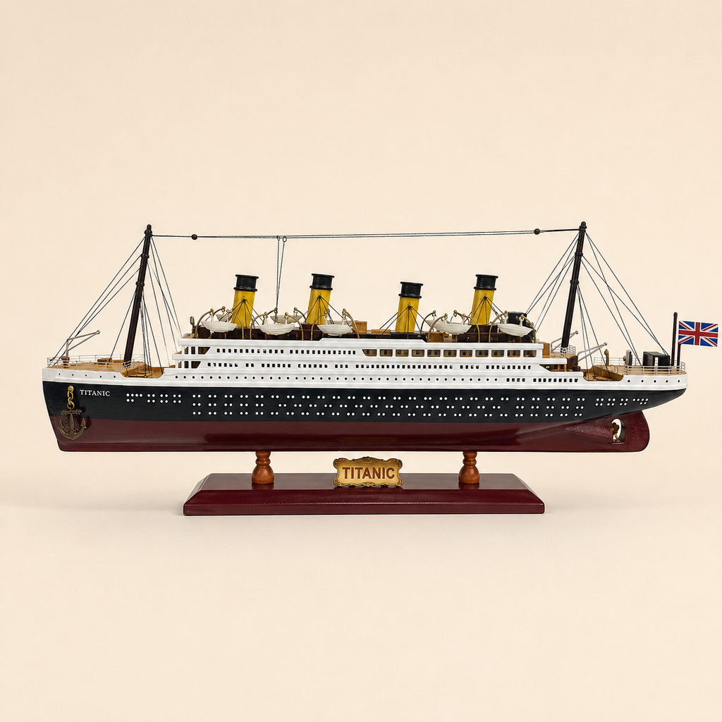 Side view of the RMS Titanic model ship featuring a black and white hull, burgundy lower hull, four yellow funnels, rows of portholes, lifeboats, rigging and Union Jack flag.