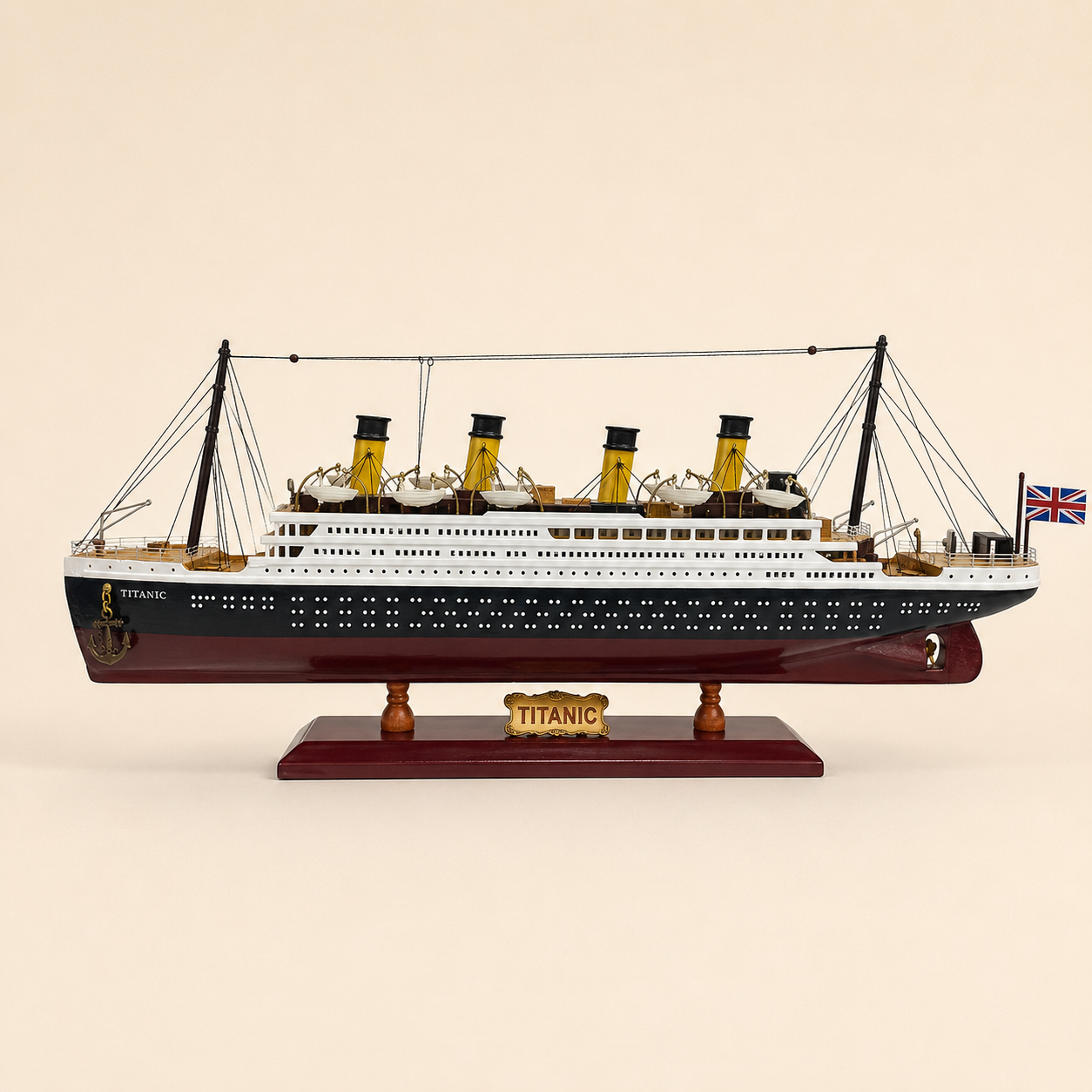 Side view of the RMS Titanic model ship featuring a black and white hull, burgundy lower hull, four yellow funnels, rows of portholes, lifeboats, rigging and Union Jack flag.