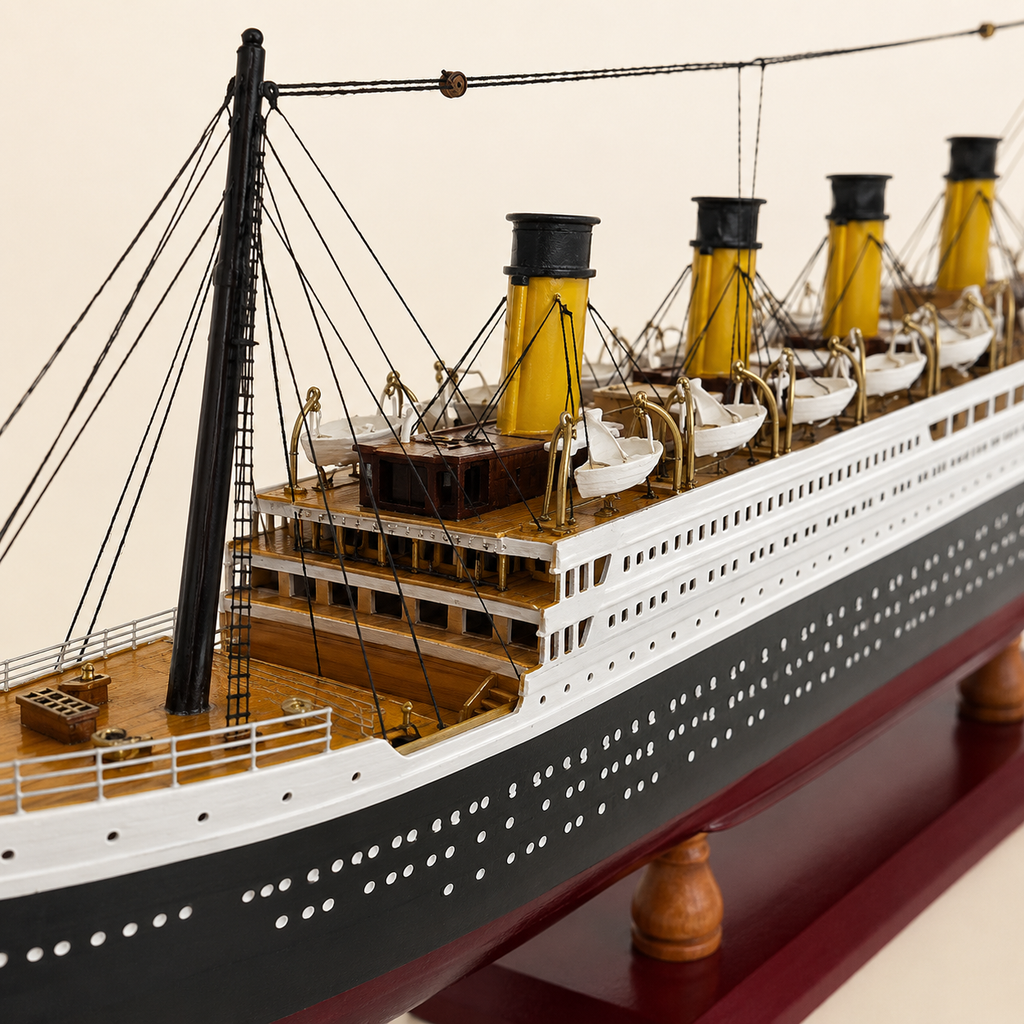 Close-up of the RMS Titanic model ship showing four yellow funnels, white lifeboats, black rigging, wooden deck, railings, windows, portholes and handcrafted miniature details.