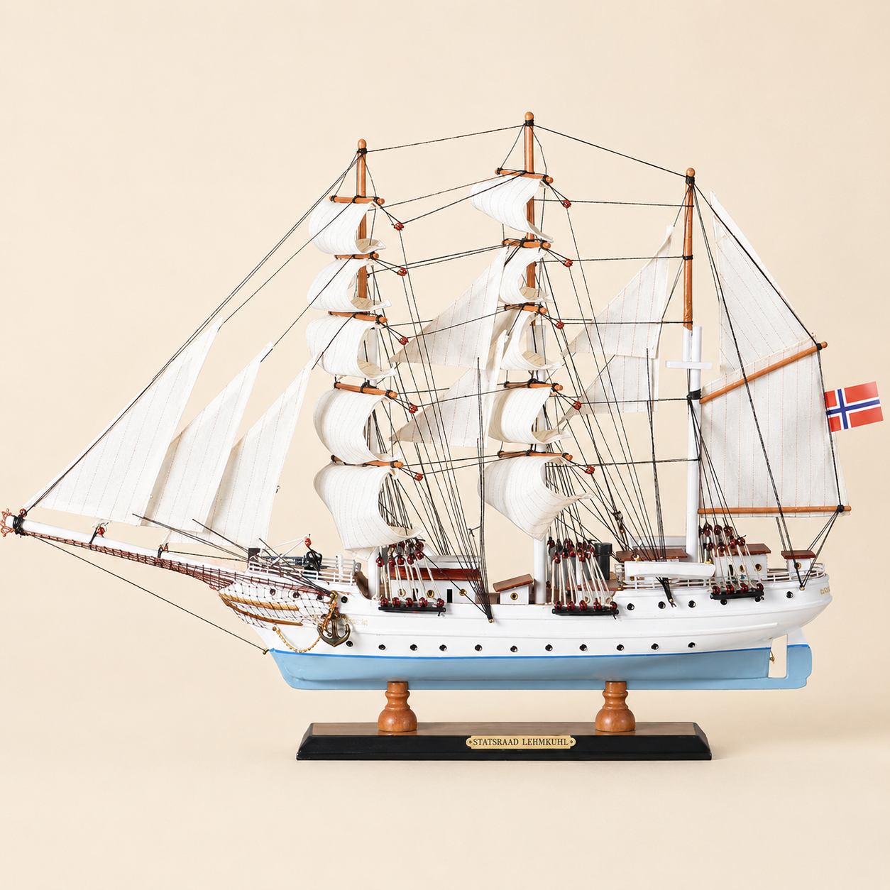 Side view of the Statsraad Lehmkuhl three-masted tall ship model featuring white sails, intricate black rigging, white upper hull, light blue lower hull and black presentation base.