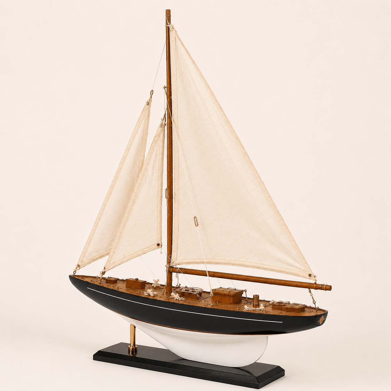 Modello di barca a vela americana a un albero, vista posteriore a 3/4, con vele bianche, scafo blu navy, ponte in teak e finiture in ottone