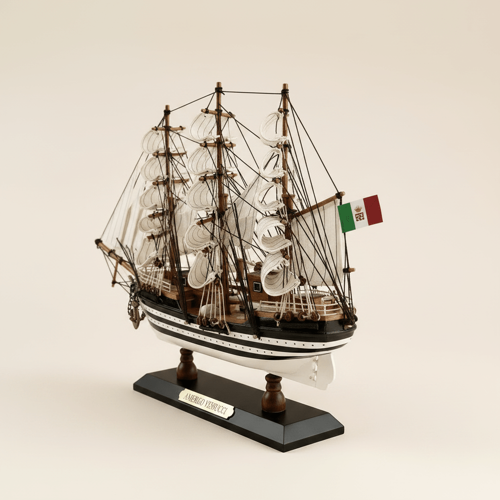Vista posterior de tres cuartos del modelo de gran velero Amerigo Vespucci de la Marina italiana sobre fondo crema, mostrando estructura de jarcia de tres mástiles, velas blancas de aparejo cuadrado, bandera de la Marina italiana en popa, casco negro y blanco a rayas y base negra con placa dorada AMERIGO VESPUCCI