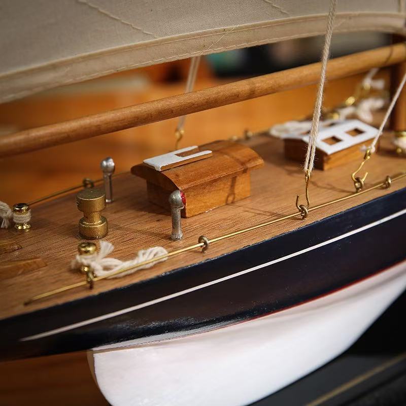 Close-up of teak deck with brass fittings, cleats, and rope detail on wooden sailboat model