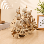 Wooden ship model on a wooden surface with a lamp and plant in the background