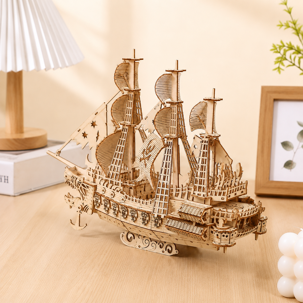 Wooden ship model on a wooden surface with a lamp and plant in the background