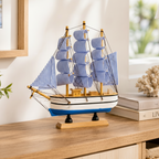Blue and white striped sailboat wooden ship model displayed in coastal home setting