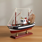 Handcrafted American shrimp boat wooden ship model on warm wooden desk – navy blue hull with white stripe, white wheelhouse, red outrigger booms, white rope rigging, metal fishing net, mahogany base with brass feet, coastal nautical home decor
