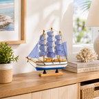 Model sailboat on a wooden surface with decor items in the background