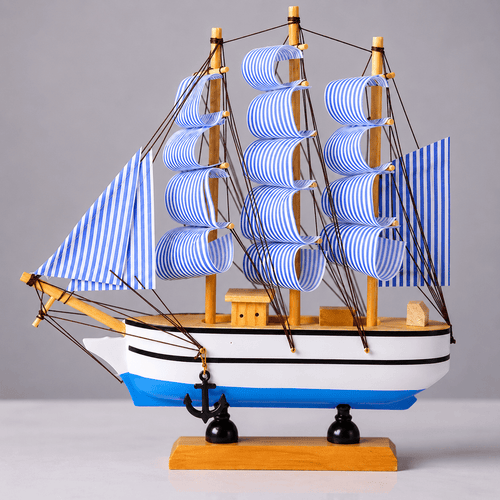 Modelo de barco con velas a rayas azules y blancas sobre fondo gris